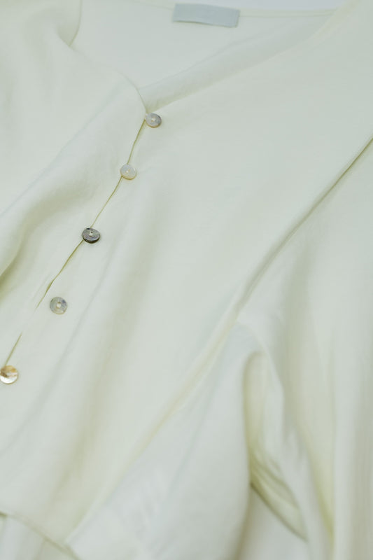 Blusa color crema con mangas globo y cierre frontal con botones.