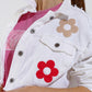 Chaqueta corta con bolsillos en el pecho y detalles de flores en blanco