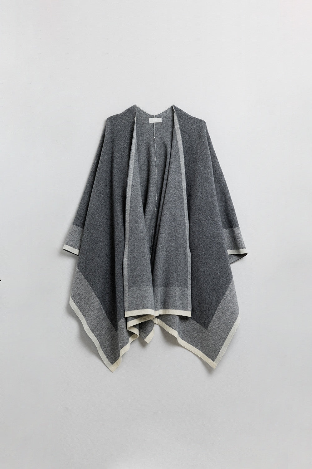 Knitted poncho in grey with ecru trim