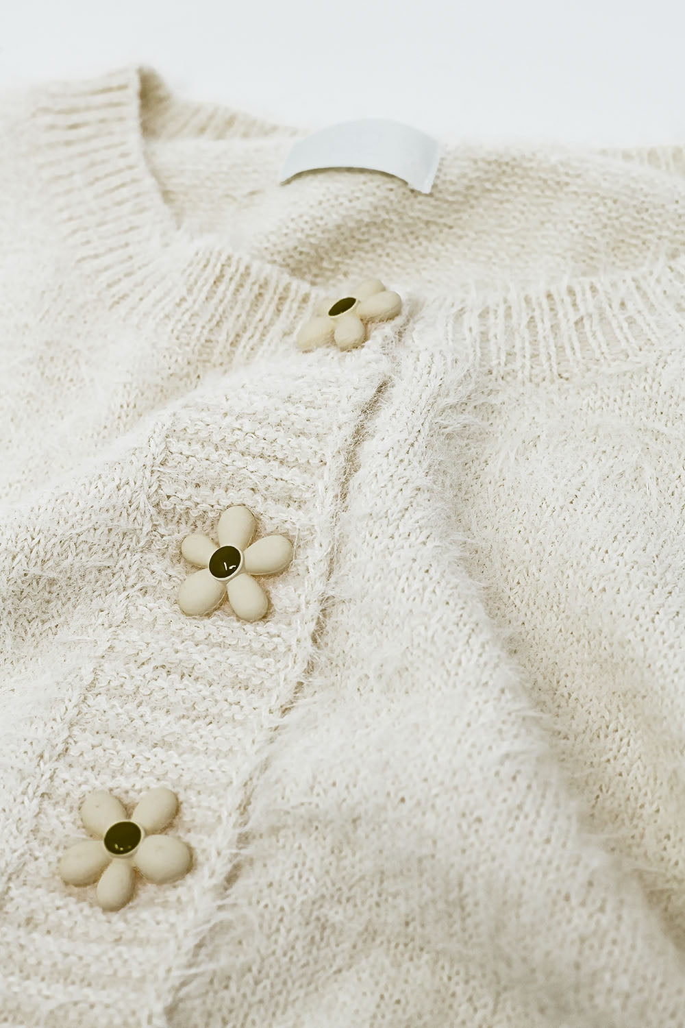 Short and fluffy cream cardigan with flower buttons