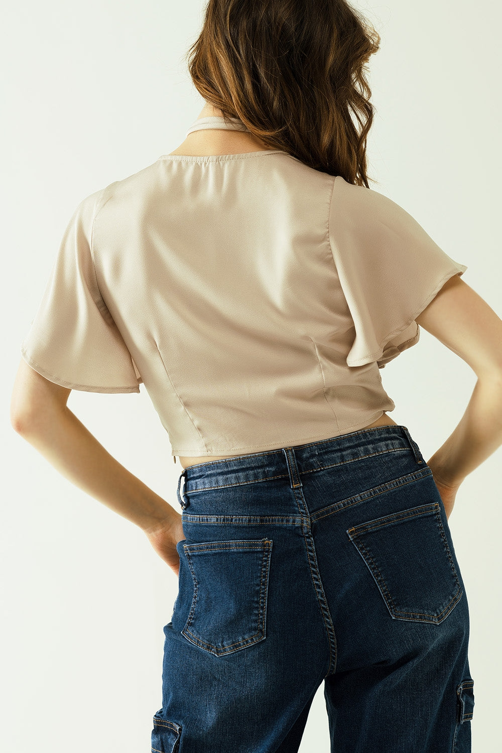 Crop top beige con escote en pico, manga corta y detalle de flores en el cuello