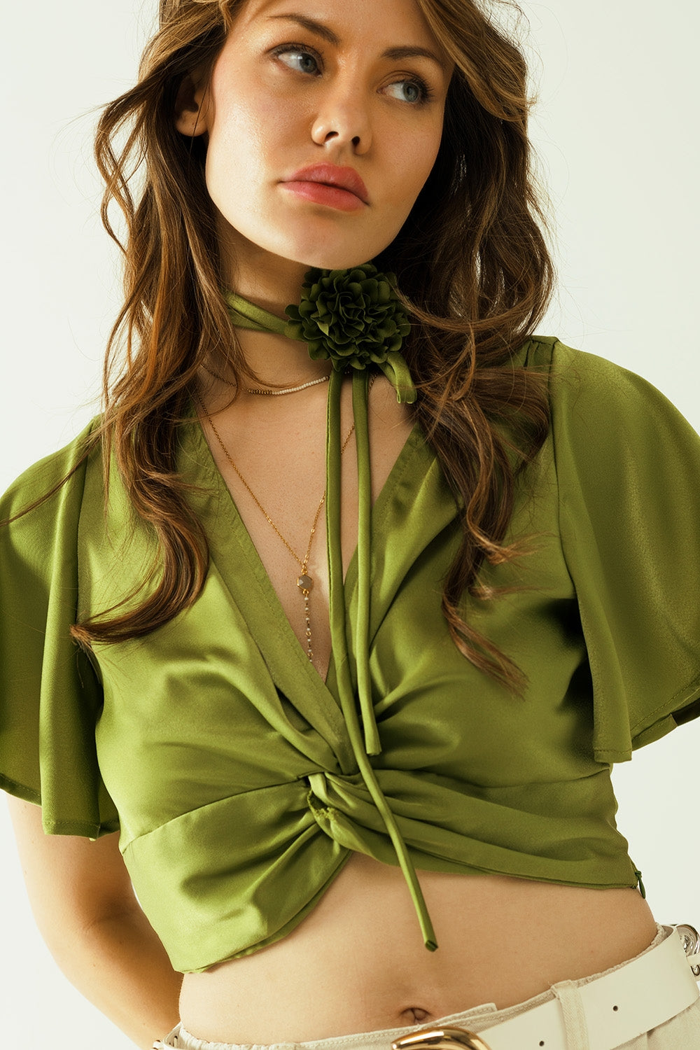 Crop top verde con escote en pico, manga corta y detalle de flores en el cuello